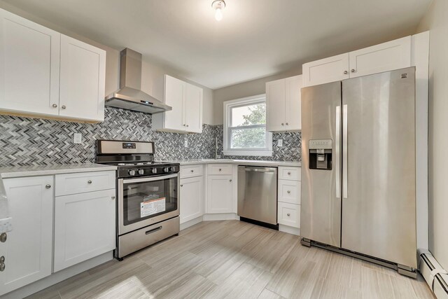 kitchen featuring stainless steel appliances, wall chimney exhaust hood, and white cabinets