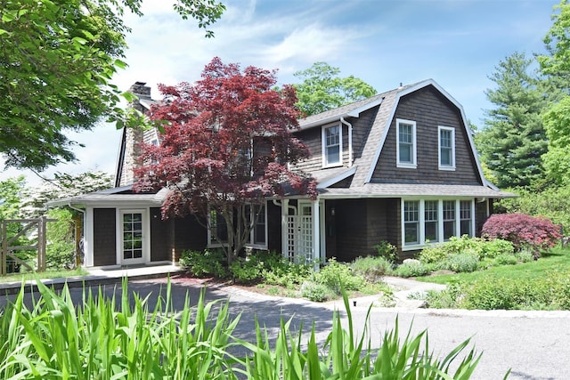 view of front of house featuring a shingled roof, a chimney, and a gambrel roof