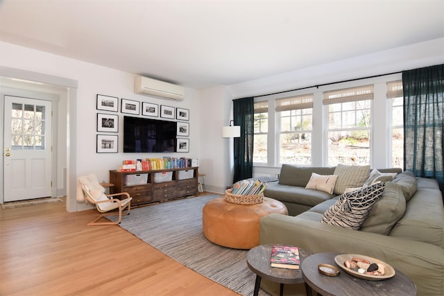 living room with light wood-type flooring, a wall mounted air conditioner, and baseboards