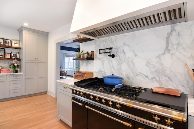 kitchen with exhaust hood, light wood-type flooring, backsplash, double oven range, and open shelves