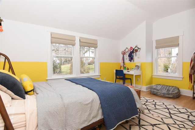 bedroom with vaulted ceiling, baseboards, and wood finished floors