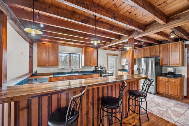 kitchen with pendant lighting, sink, wooden counters, kitchen peninsula, and stainless steel appliances