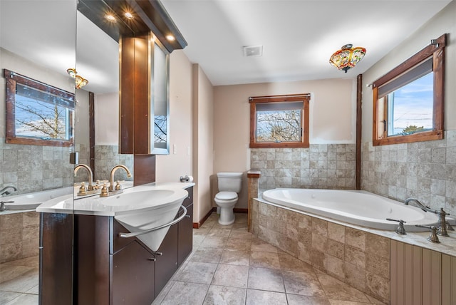 bathroom with tile patterned floors, vanity, toilet, and tiled bath