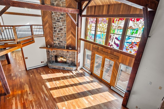 living room with a baseboard heating unit, hardwood / wood-style floors, a high ceiling, a fireplace, and french doors