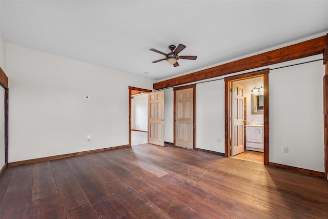 unfurnished bedroom with ceiling fan, ensuite bath, a barn door, and hardwood / wood-style floors