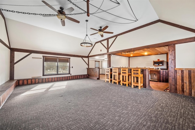 unfurnished living room featuring high vaulted ceiling, wood walls, indoor bar, carpet, and ceiling fan