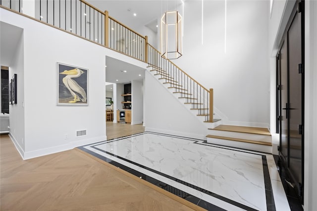 foyer featuring a towering ceiling and parquet floors