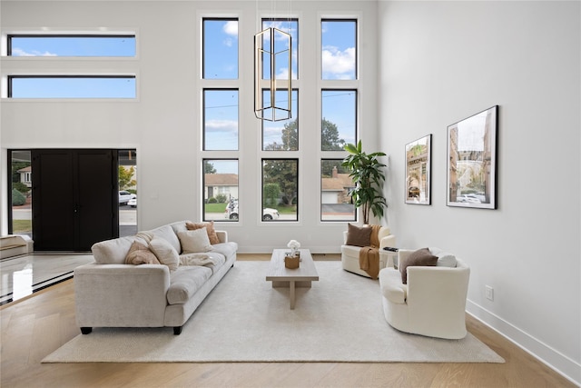 living room featuring a notable chandelier, hardwood / wood-style floors, a towering ceiling, and plenty of natural light