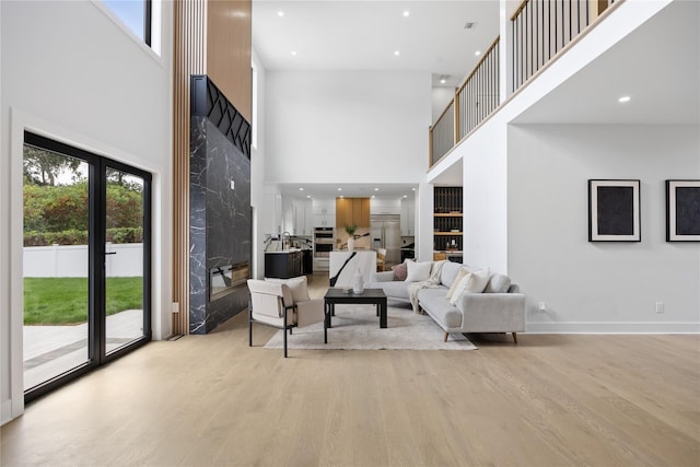 living room featuring sink, light wood-type flooring, and a towering ceiling