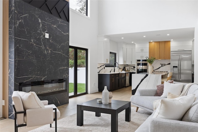 living room with sink, a high ceiling, and a premium fireplace