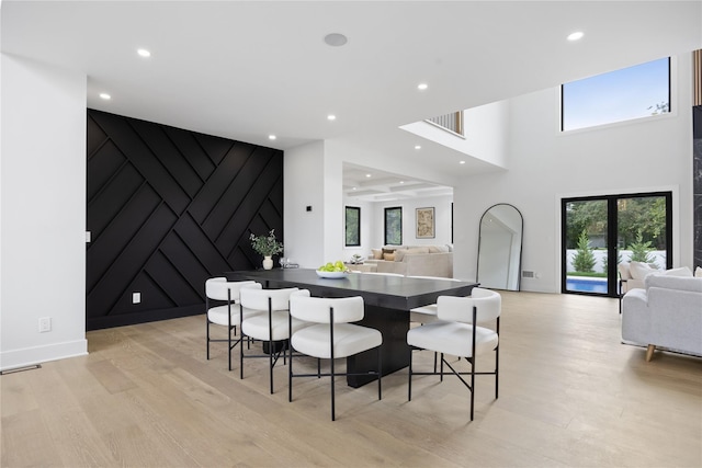 dining area with a high ceiling and light hardwood / wood-style flooring