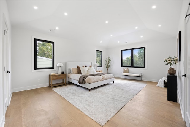 bedroom with multiple windows, vaulted ceiling, and light hardwood / wood-style flooring