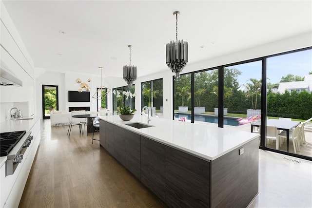 kitchen featuring sink, stainless steel gas stovetop, an island with sink, and dark brown cabinets