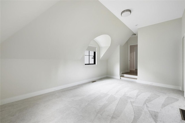 additional living space with vaulted ceiling and light carpet