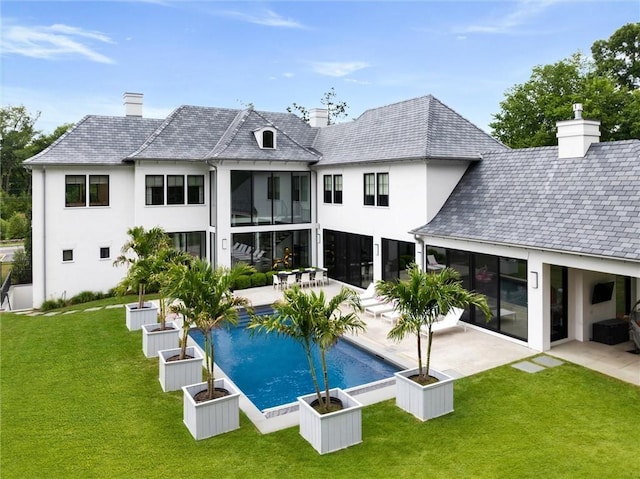 rear view of house with a patio, a lawn, and a sunroom