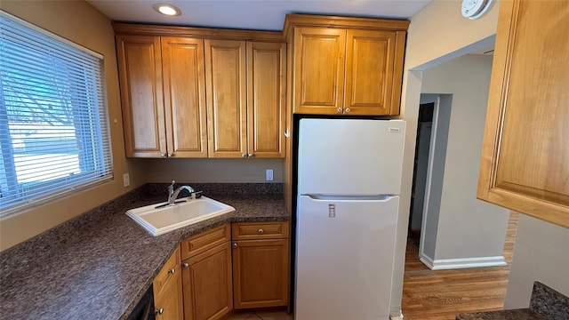 kitchen featuring white refrigerator, wood-type flooring, and sink