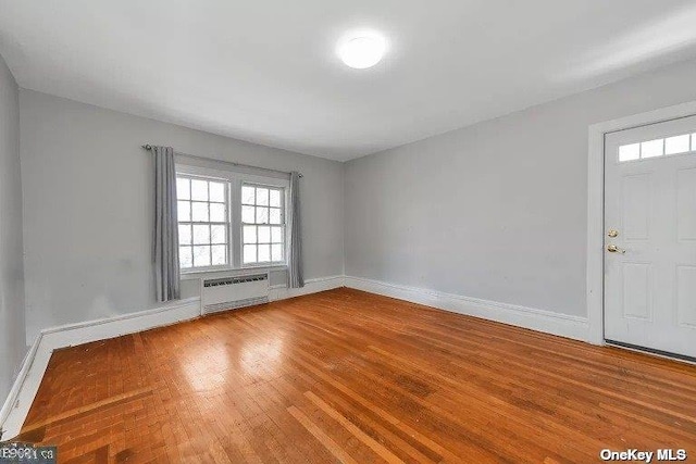 unfurnished room featuring radiator heating unit and wood-type flooring