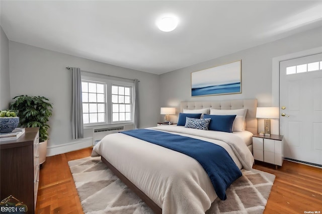 bedroom featuring radiator heating unit and hardwood / wood-style floors