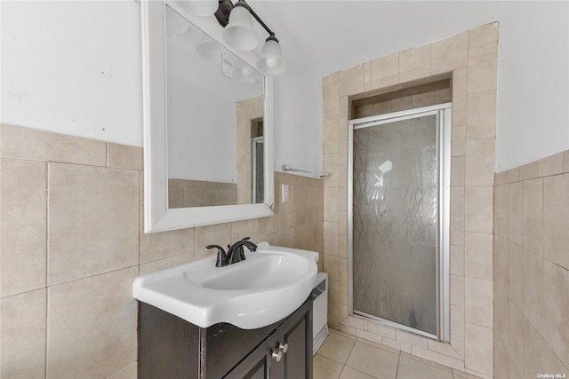 bathroom with tile walls, a shower with door, tile patterned floors, and vanity