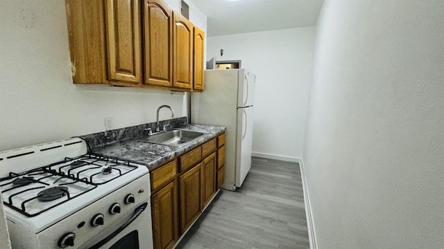 kitchen with sink, white appliances, and light wood-type flooring