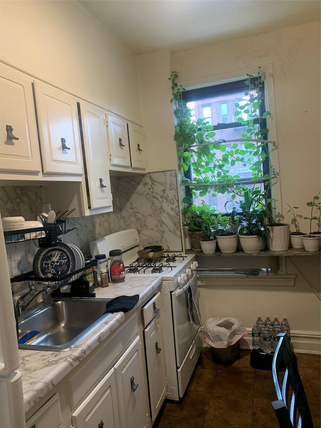 kitchen featuring white cabinets, backsplash, sink, and white range with gas cooktop