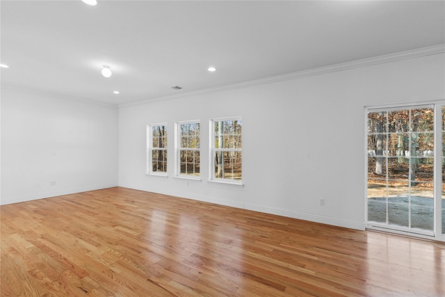 spare room with light wood-type flooring, a healthy amount of sunlight, and crown molding