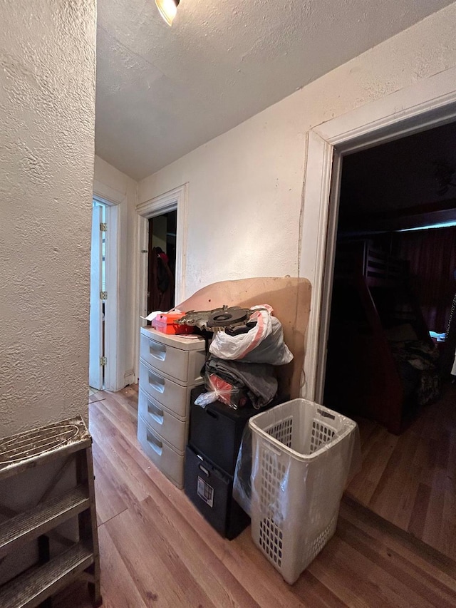 interior space with a textured ceiling, light hardwood / wood-style floors, and a closet