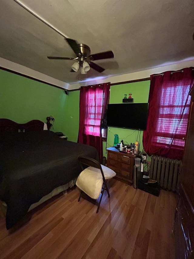 bedroom with wood-type flooring, radiator heating unit, and ceiling fan