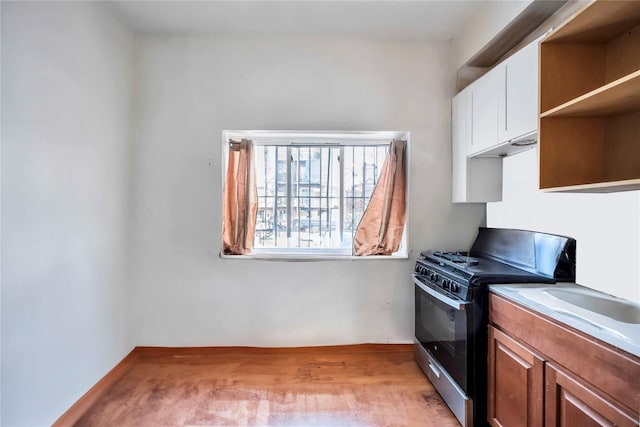 kitchen with white cabinets, light hardwood / wood-style flooring, and gas range