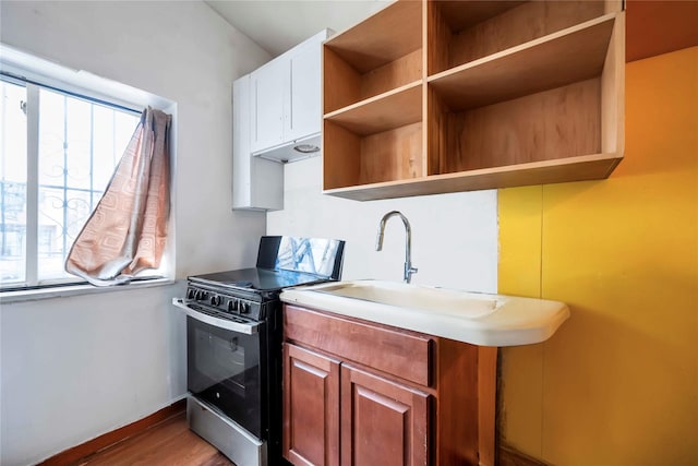 kitchen featuring stainless steel gas range oven, light hardwood / wood-style flooring, and sink