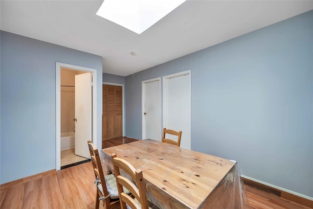 dining room with a skylight and light wood-type flooring