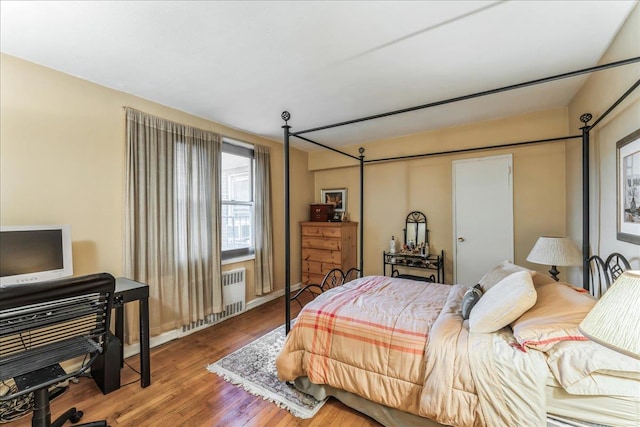 bedroom featuring radiator and hardwood / wood-style floors