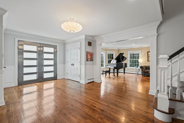 foyer entrance featuring hardwood / wood-style floors, decorative columns, baseboard heating, french doors, and crown molding