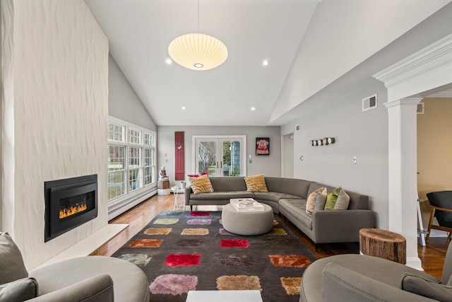 living room featuring decorative columns, hardwood / wood-style floors, high vaulted ceiling, and a baseboard radiator