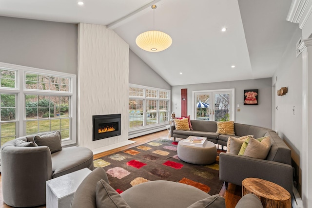 living room with wood-type flooring, plenty of natural light, a large fireplace, and a baseboard radiator