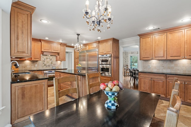 kitchen with appliances with stainless steel finishes, a center island, decorative light fixtures, tasteful backsplash, and sink