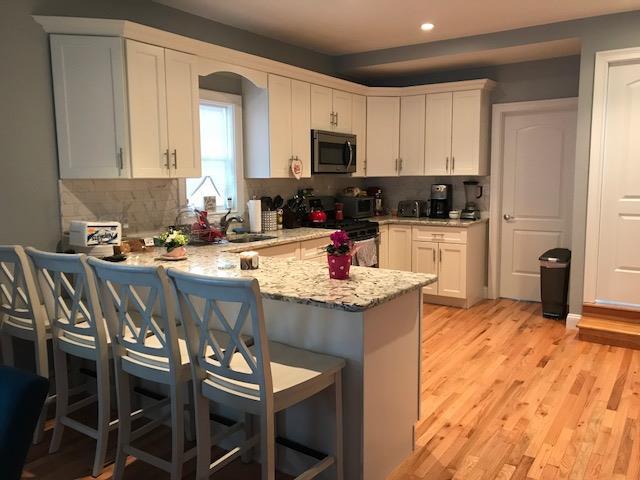 kitchen with sink, white cabinets, a kitchen bar, stove, and kitchen peninsula