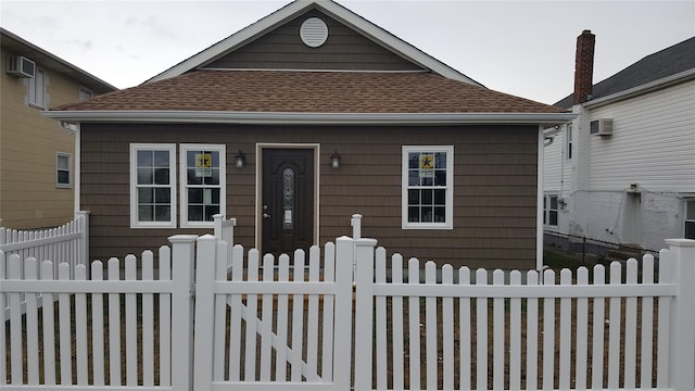 bungalow-style home with a wall mounted air conditioner