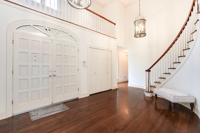 entryway with an inviting chandelier, dark hardwood / wood-style flooring, crown molding, and a towering ceiling