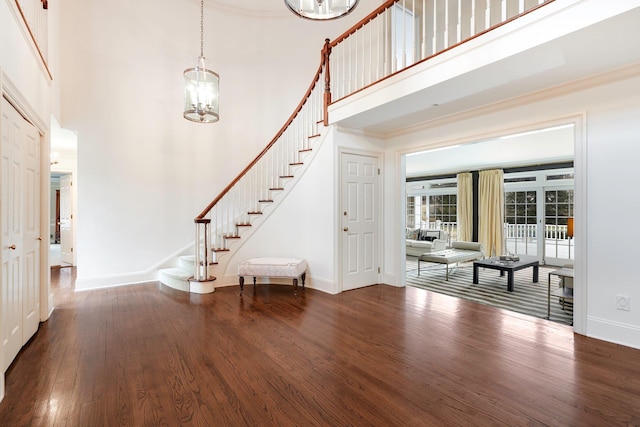 entrance foyer featuring a towering ceiling, ornamental molding, a chandelier, and hardwood / wood-style flooring