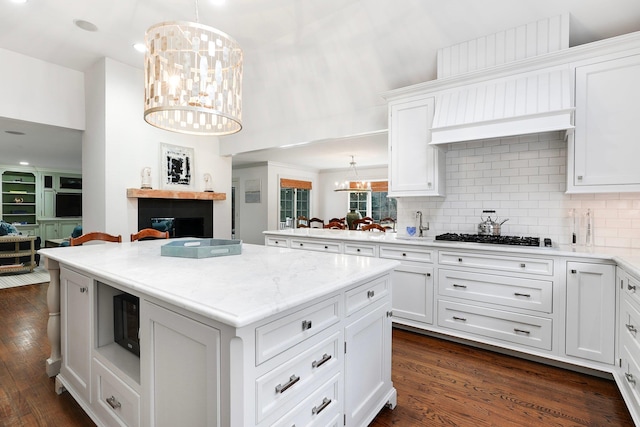 kitchen featuring tasteful backsplash, white cabinets, stainless steel gas stovetop, and a chandelier