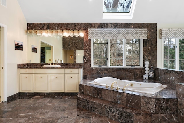 bathroom featuring a relaxing tiled tub, tile walls, vanity, and a skylight