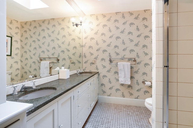 bathroom featuring toilet, vanity, and a skylight