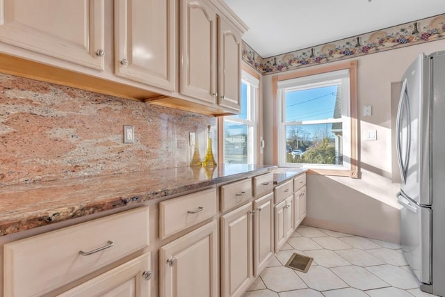 kitchen featuring light tile patterned floors, light stone countertops, and stainless steel refrigerator