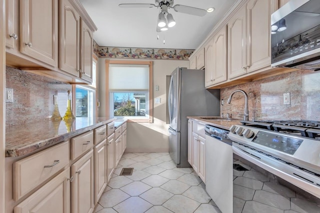 kitchen with sink, stainless steel appliances, ceiling fan, and light stone countertops