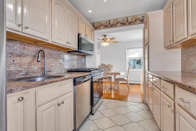 kitchen featuring light stone countertops, appliances with stainless steel finishes, sink, backsplash, and ceiling fan