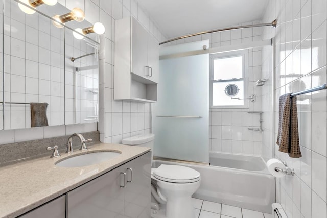 full bathroom featuring toilet, combined bath / shower with glass door, tile walls, a baseboard heating unit, and tile patterned floors