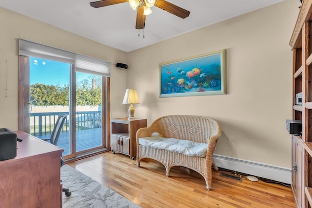 sitting room featuring ceiling fan, a baseboard heating unit, and light wood-type flooring