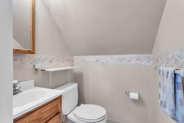 bathroom featuring toilet, lofted ceiling, and vanity