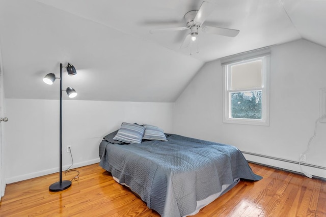 bedroom with baseboard heating, hardwood / wood-style floors, vaulted ceiling, and ceiling fan